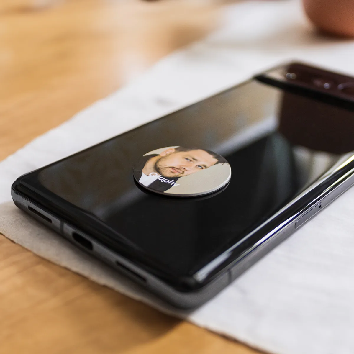 NFC Sticker geplakt op de achterkant van een mobiel met een opdruk van een persoon